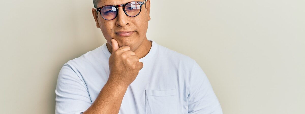 Young latin man wearing casual clothes and glasses thinking concentrated about doubt with finger on
